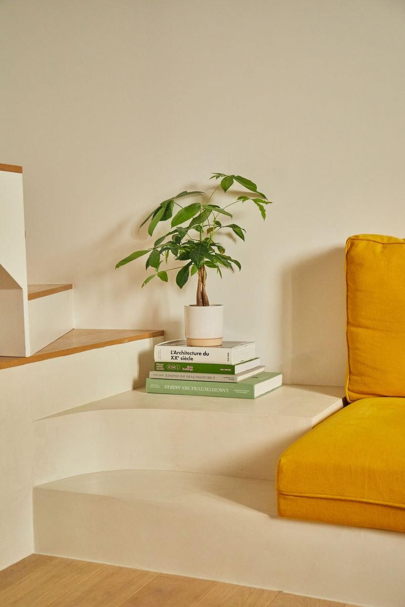 Banquette maçonnée arrondie au pied de l’escalier, coussins jaunes