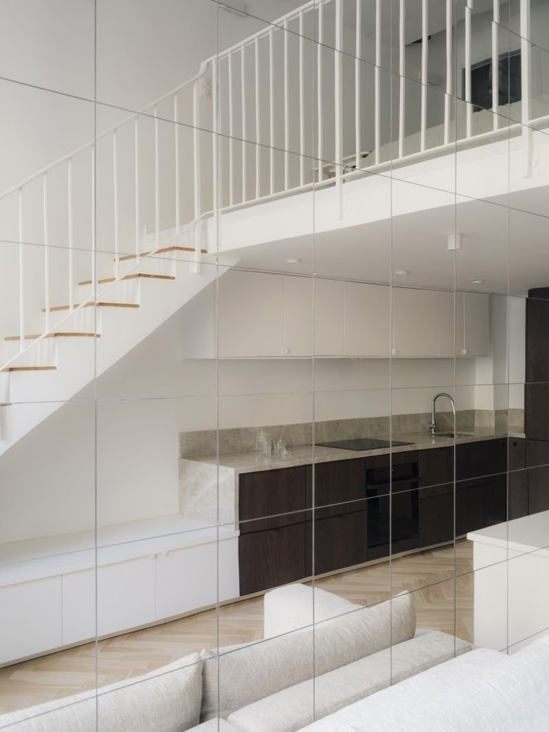 Escalier et mezzanine reflétés dans le mur de miroirs du séjour