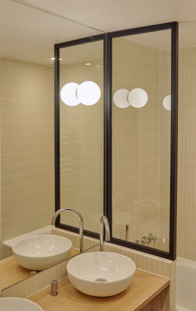 Salle de bains : deux vasques, miroir et paroi vitrée à cadre noir