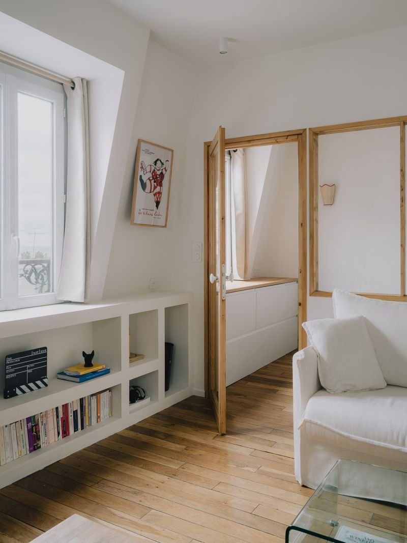 Séjour mansardé, bibliothèque basse et porte vitrée en bois de la chambre