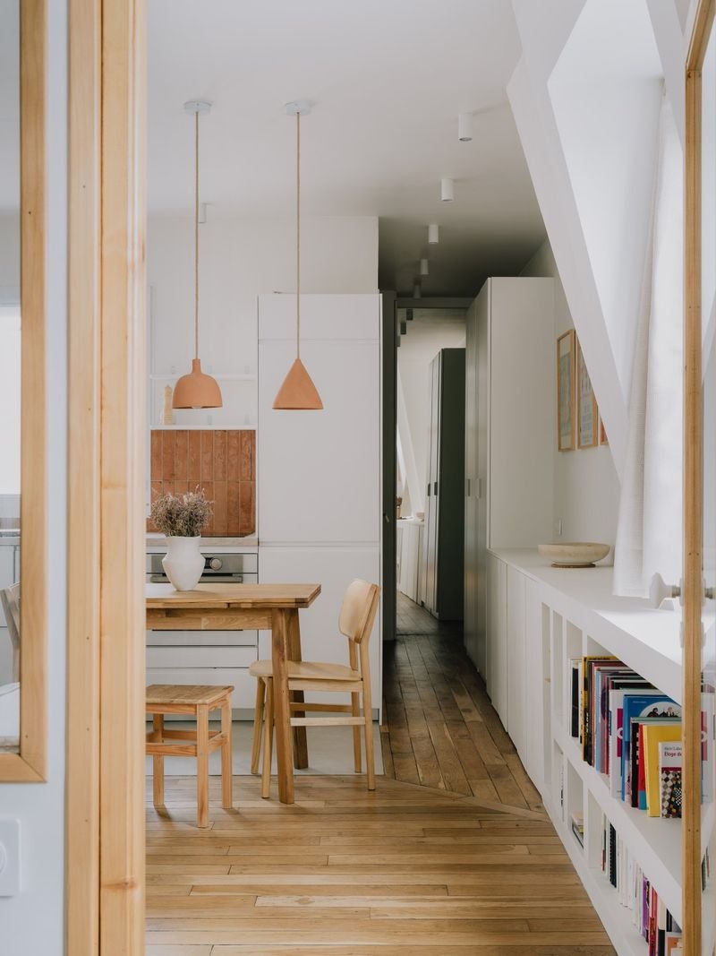 Pièce de vie mansardée en enfilade : coin repas, cuisine et bibliothèque basse