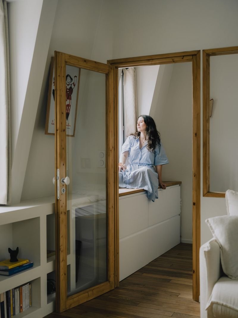 Banquette-coffre sous la fenêtre de la chambre, vue par la porte vitrée en bois